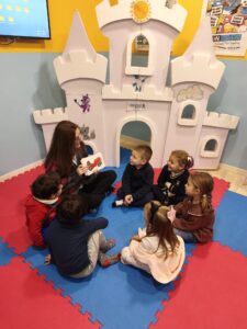 Vemos una imagen con niños que están felices en una clase de inglés junto con su profesora